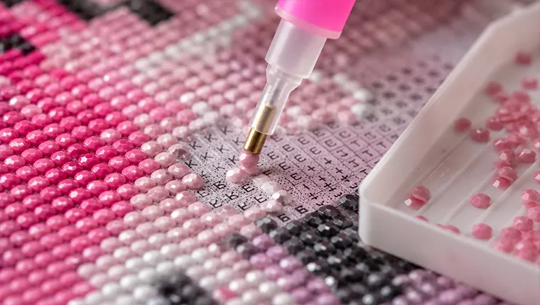 Diamond painting pen placing a resin drill on a numbered canvas