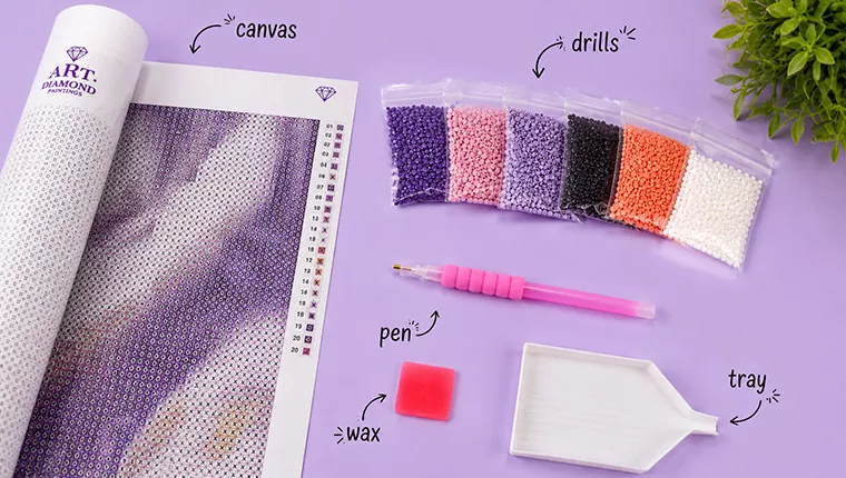 Flat-lay of diamond painting kit contents: canvas, drills, pen, wax and tray