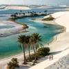 Turquoise desert oasis surrounded by white sand dunes and palm trees